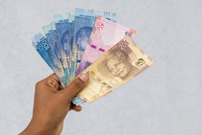 South African Rand currency in female hand, including 20, 50, and 100 Rand notes. Financial concept of wealth and economy.
