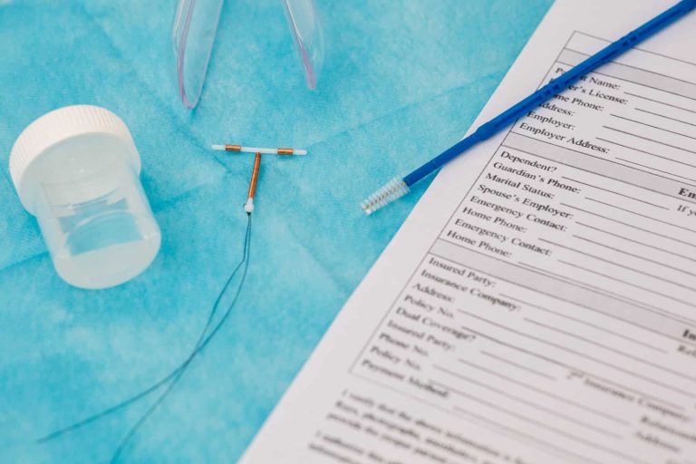 Gynecology consult shows an IUD, pamphlet, and patient paperwork on a blue surface, highlighting women's health. Birth control