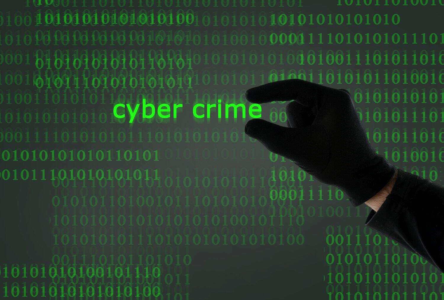 hacker hand holding cyber crime text from computer screen