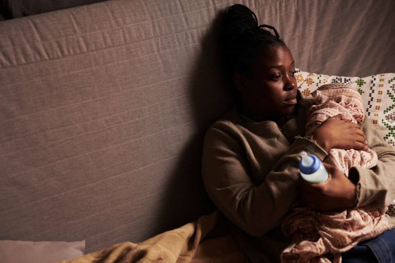 Miserable young woman holding baby
