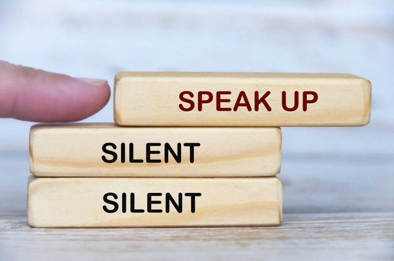 Hand pushing wooden block with speak up text. Speak up and courage concept