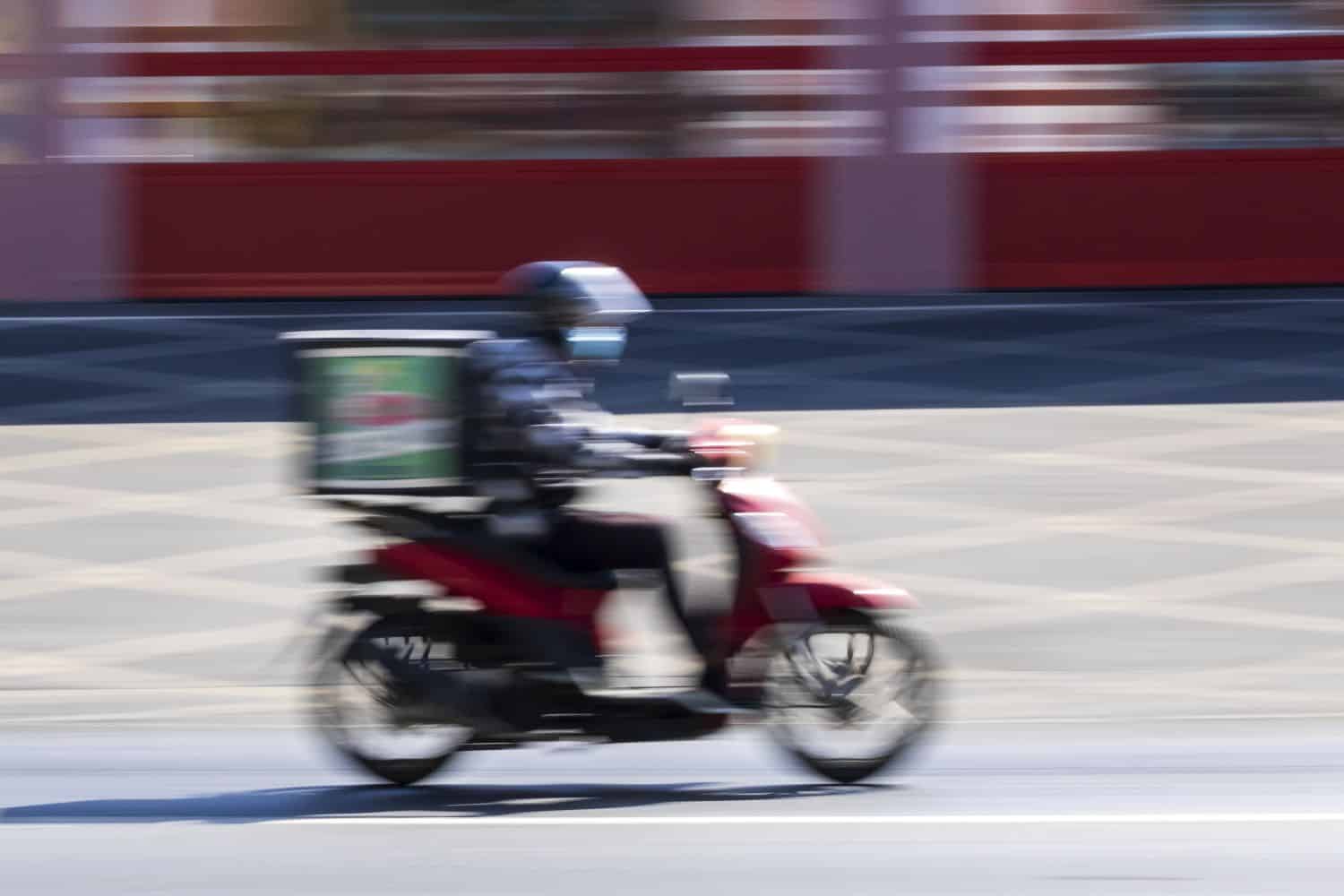 Delivery man on motorbike in motion