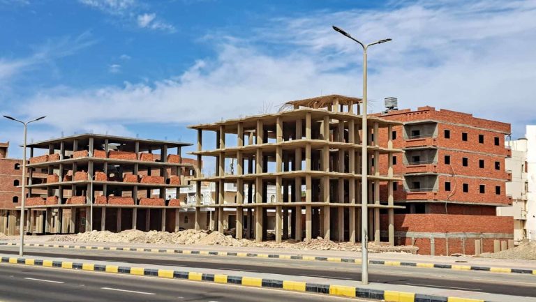 Construction site featuring unfinished buildings with exposed brick and concrete structures under a clear blue sky, showcasing urban development and architectural progress. Hurghada, Egypt, Red Sea