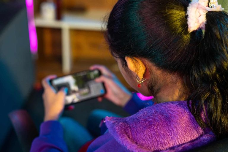 focus on girl, Shoulder shot of girl playing live video game on mobile phone at home - concept of relaxation, championship and tournament.