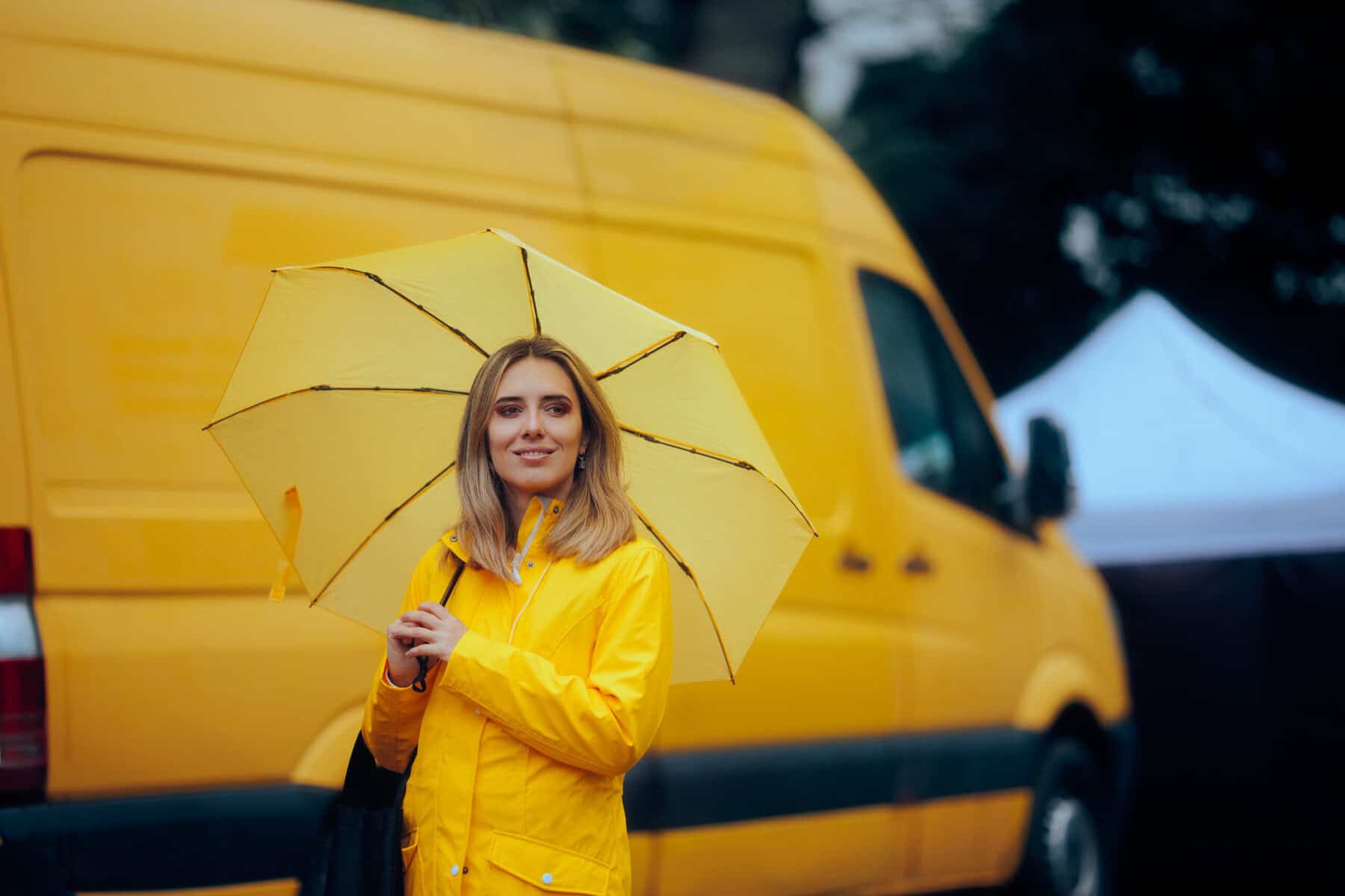 Woman with Yellow Umbrella Standing in Front of a Van