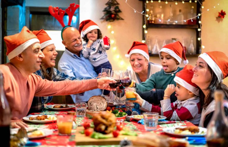 Large multi generation family toasting at christmas supper fest - Winter holiday xmas concept with grand parents and children eating together at home party reunion - Warm filter with focus on glasses