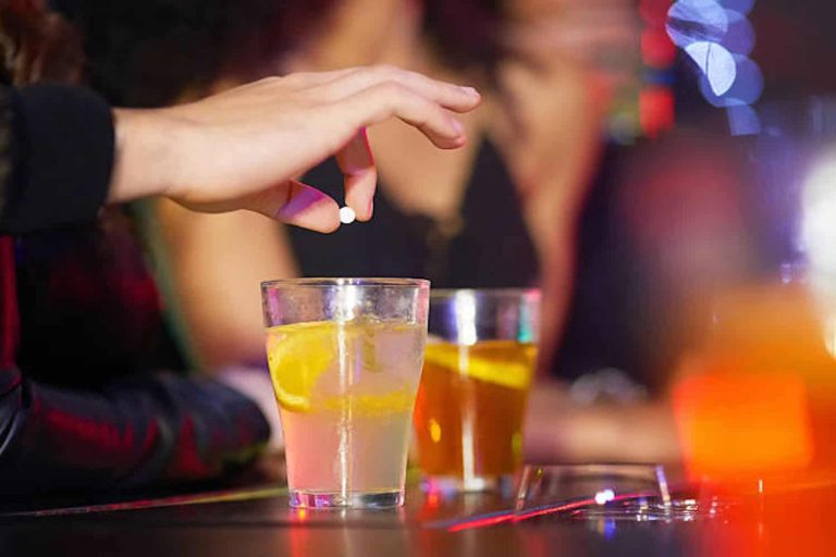 Closeup shot of a man drugging a woman's drink in a nightclub