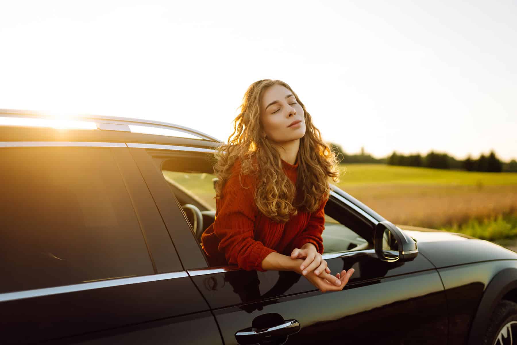 Relaxed woman on summer road trip enjoying window view.
