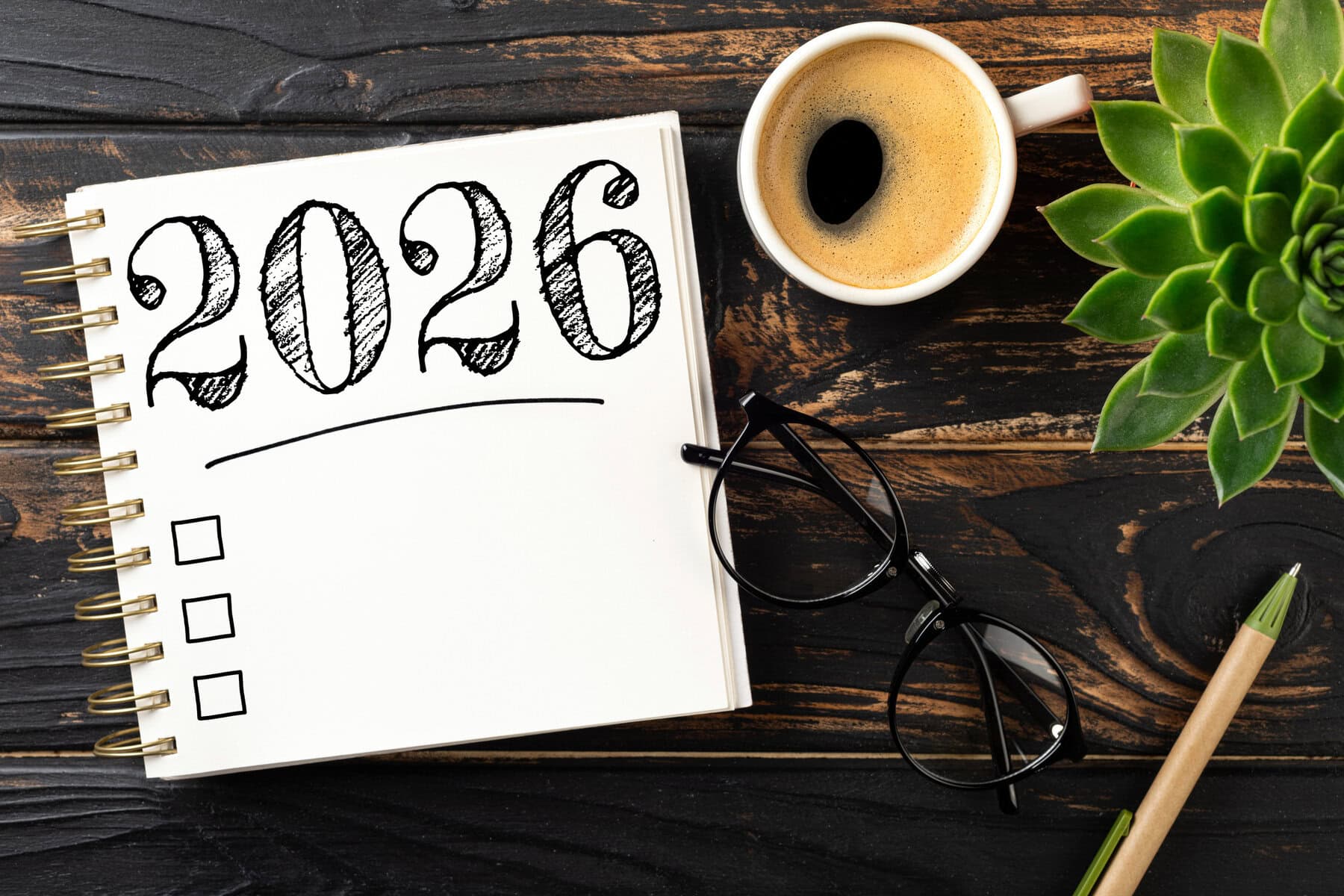 New year resolutions 2026 on desk. 2026 goals list with notebook, coffee cup, plant on wooden table. Resolutions, plan, goals, action, checklist, idea concept. New Year 2026 resolutions