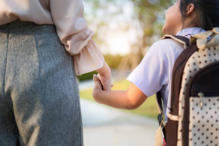 Close up of Happy Asian mother and daughter preschool student walking to school. Beginning of lessons. First day of fall. Parenthood or love and bonding expression concept.