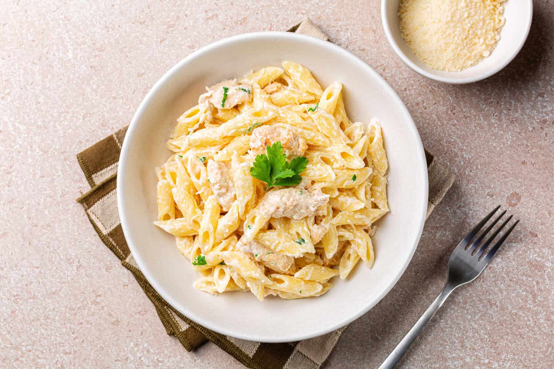 Chicken Alfredo penne, creamy pasta wich parmesan cheese in a white plate. Directly above.