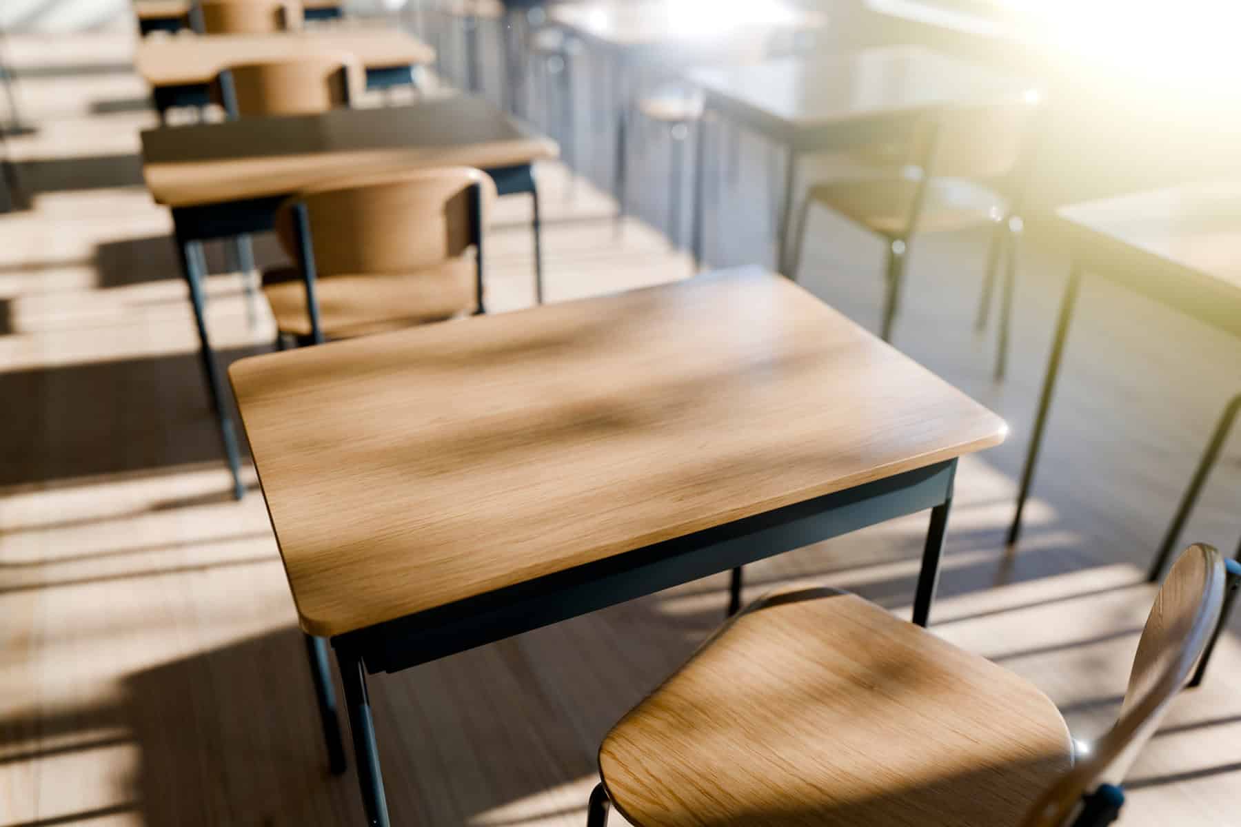 Minimalist Classroom Setting with Wooden Desks emphasizing a peaceful learning environment filled with natural light.  3d render.