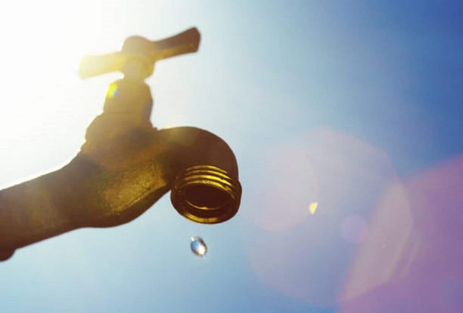 A single droplet falls from a faucet, symbolizing water scarcity or drought.