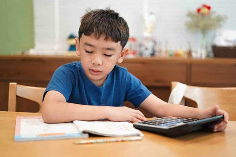 Boy is using a calculator to do his homework.