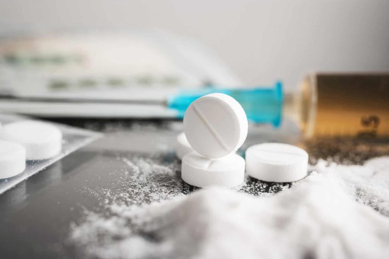 White pills, drugs or medical treatment, cocaine or heroin white powder, syringe with a dose and us dollar cash. Drug abuse and addiction concept