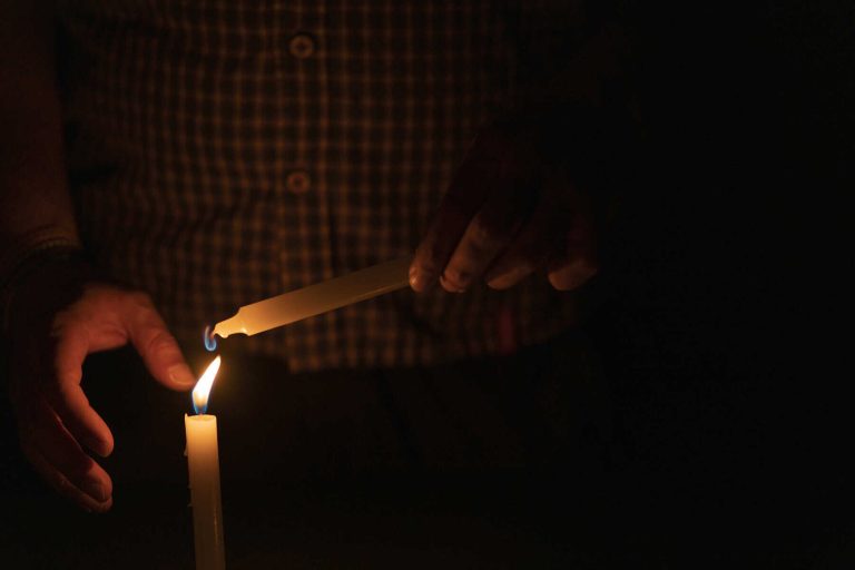 Close up of man's hand lighting a candle in the dark