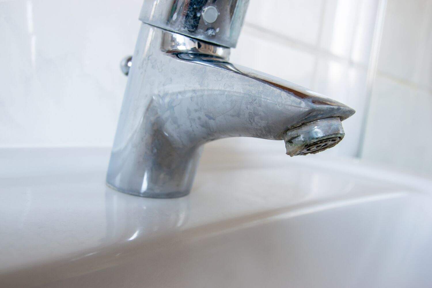 Metal tap with much water  limescale water in bathroom.