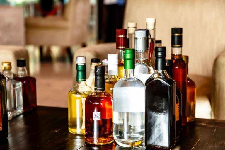 Many different bottles of alcoholic beverages are on the table.