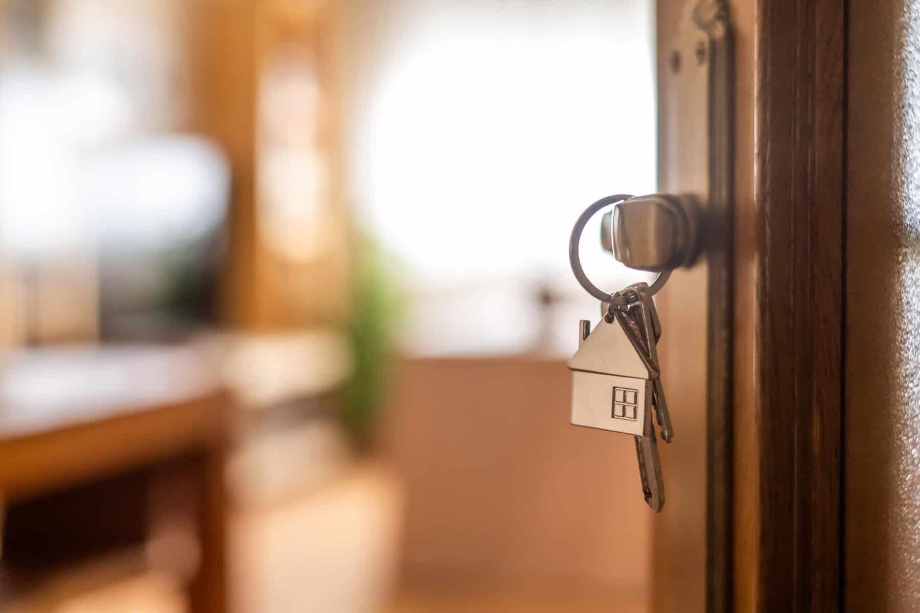 House-shaped keys are hanging from the door knob of a new home, representing the exciting moment of acquiring property and starting a fresh chapter