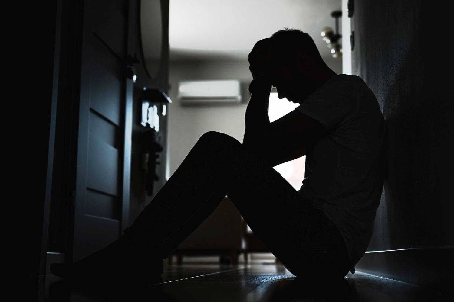 Depressed man sitting on floor in dark room