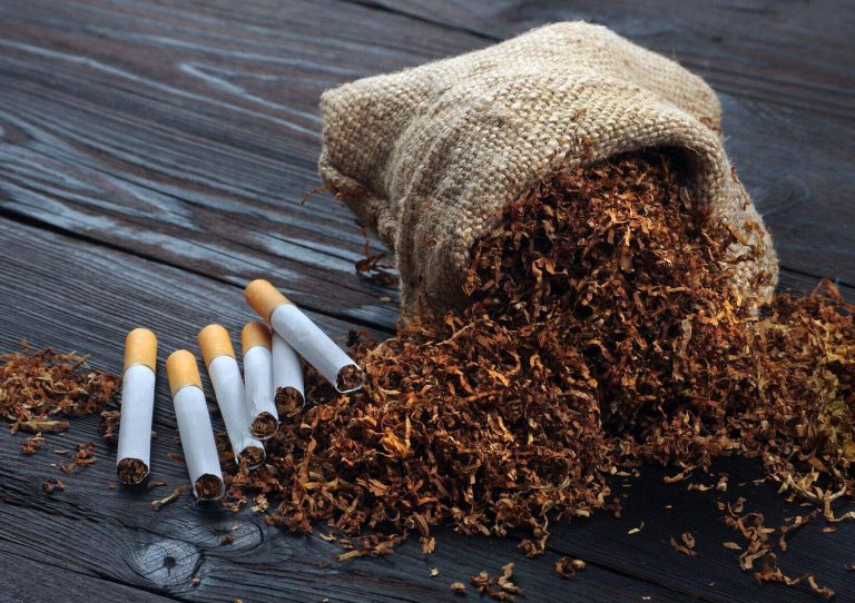 dry cut tobacco leaf and cigarettes on a wooden table. tobacco in a bag