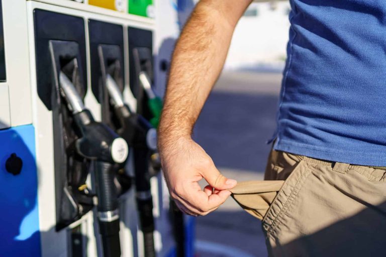 Man with empty pockets in sign of high fuel prices at gas stations.