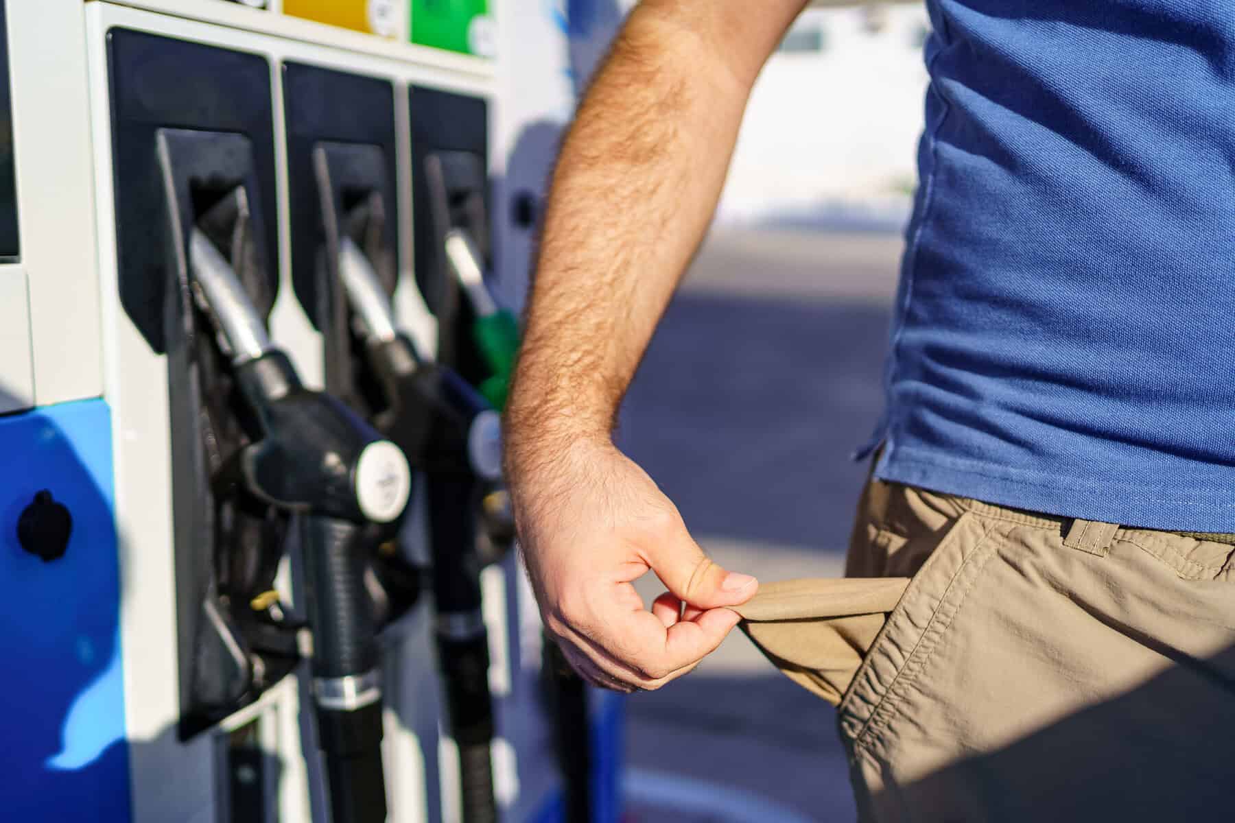 Man with empty pockets in sign of high fuel prices at gas stations.