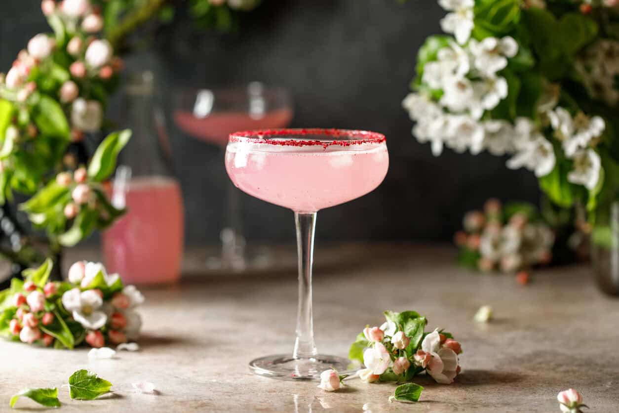 Spring and summer refreshing pink cocktail with apple blossom on light background. Pink summer cocktail