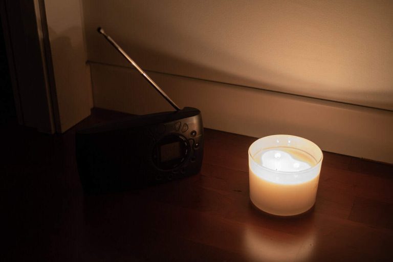 Emergency candlelight and portable radio on the floor during a power outage, symbolizing survival, communication, and preparedness in times of electricity loss
