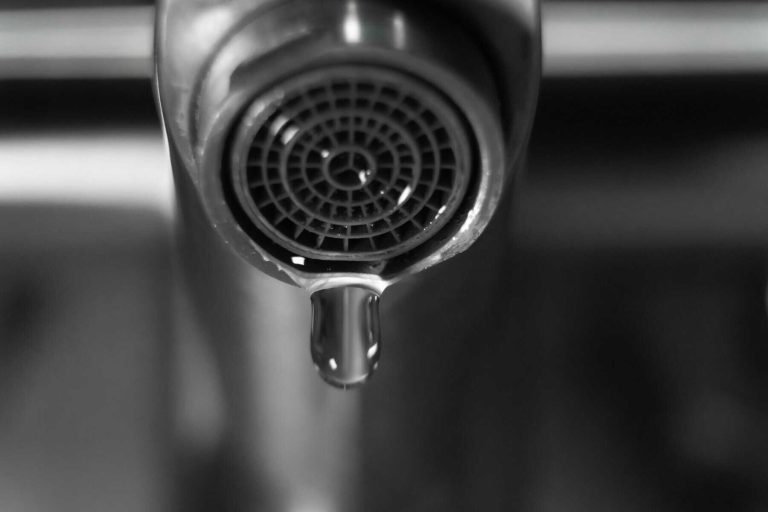 Close-up of a dripping faucet in monochrome, highlighting water waste, conservation, and plumbing problems, urging viewers to address leaks and promote responsible water usage