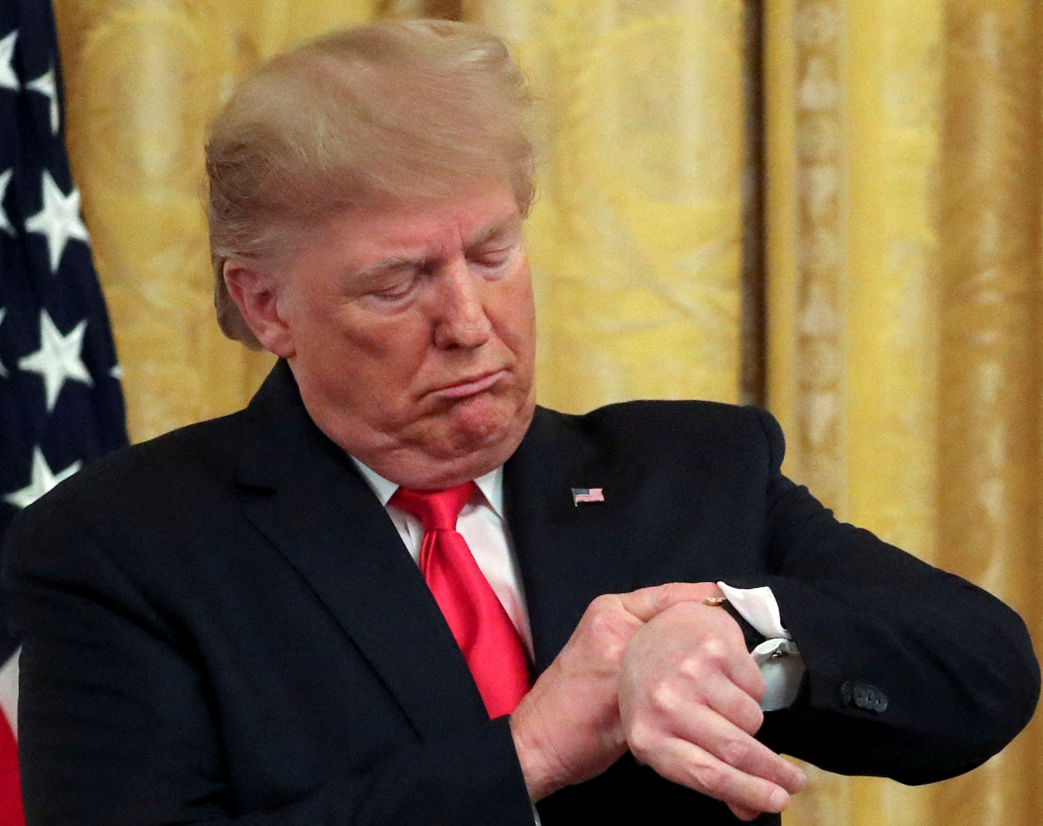FILE PHOTO: U.S. President Trump checks his watch during an event in the East Room of the White House in Washington, D.C.