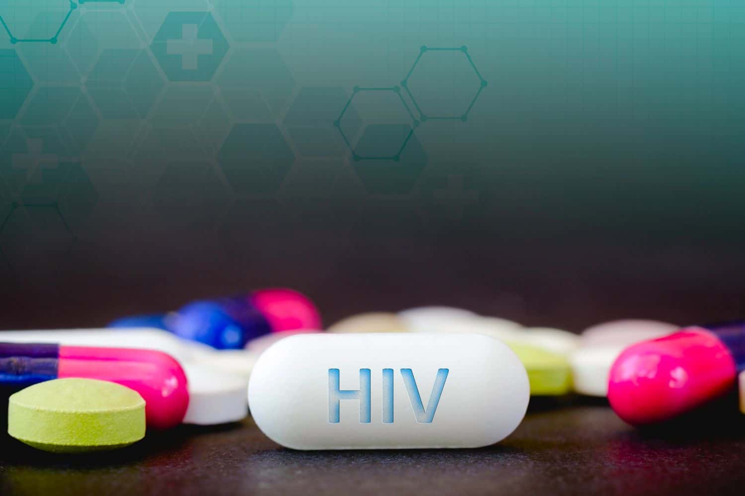 In this photo illustration pills of pharmaceutical drugs of various colors. Text HIV in one white pill. Healthcare and medicine concept