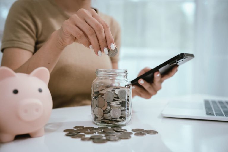 An Asian woman plans to divide her money into coins and a piggy bank, symbolizing budgeting, financial planning, saving, and smart money management.