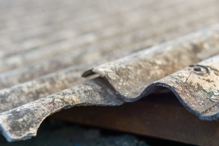 The corrugated asbestos roof has aged and deteriorated, its surface faded by the weather