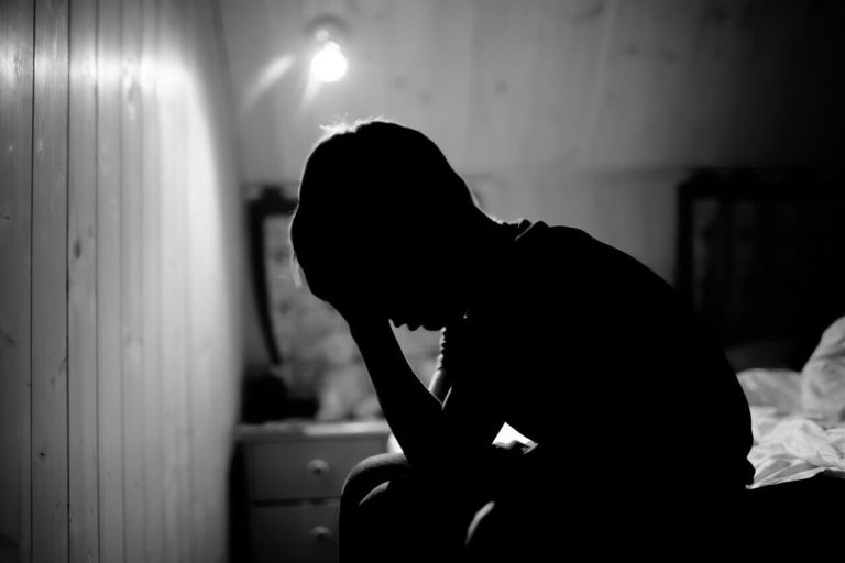 Sad little boy crying in the dark room.