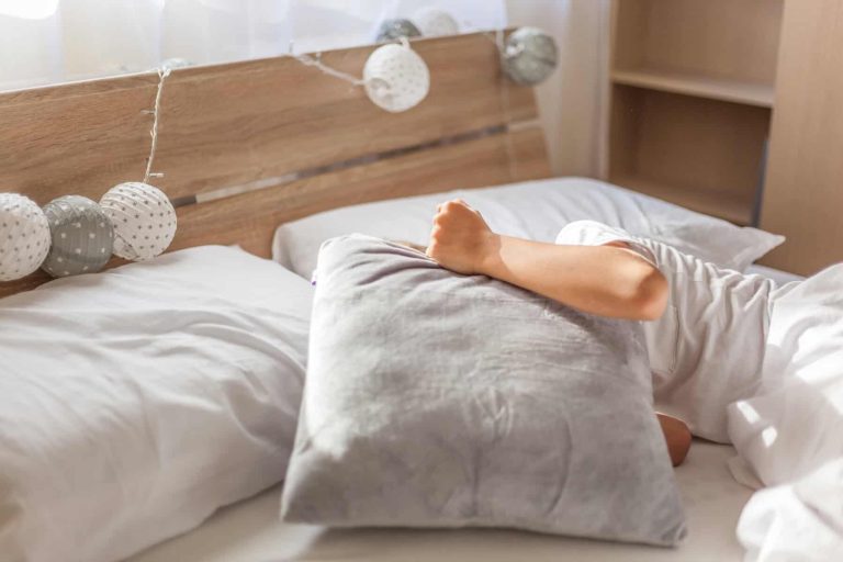High Angle View Of Cheerful Boy Lying On Bed At Home