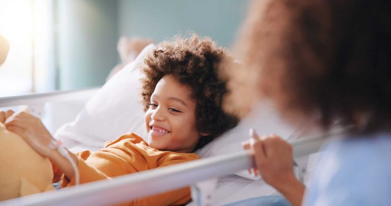 Kid, mother and smile in hospital bed with teddy bear for healthcare, medical support or surgery recovery. Mom, sick child and happy patient with toy for play, hand and healing illness with family