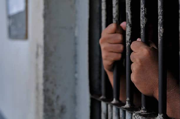 prisoner's hands behind bars, prison