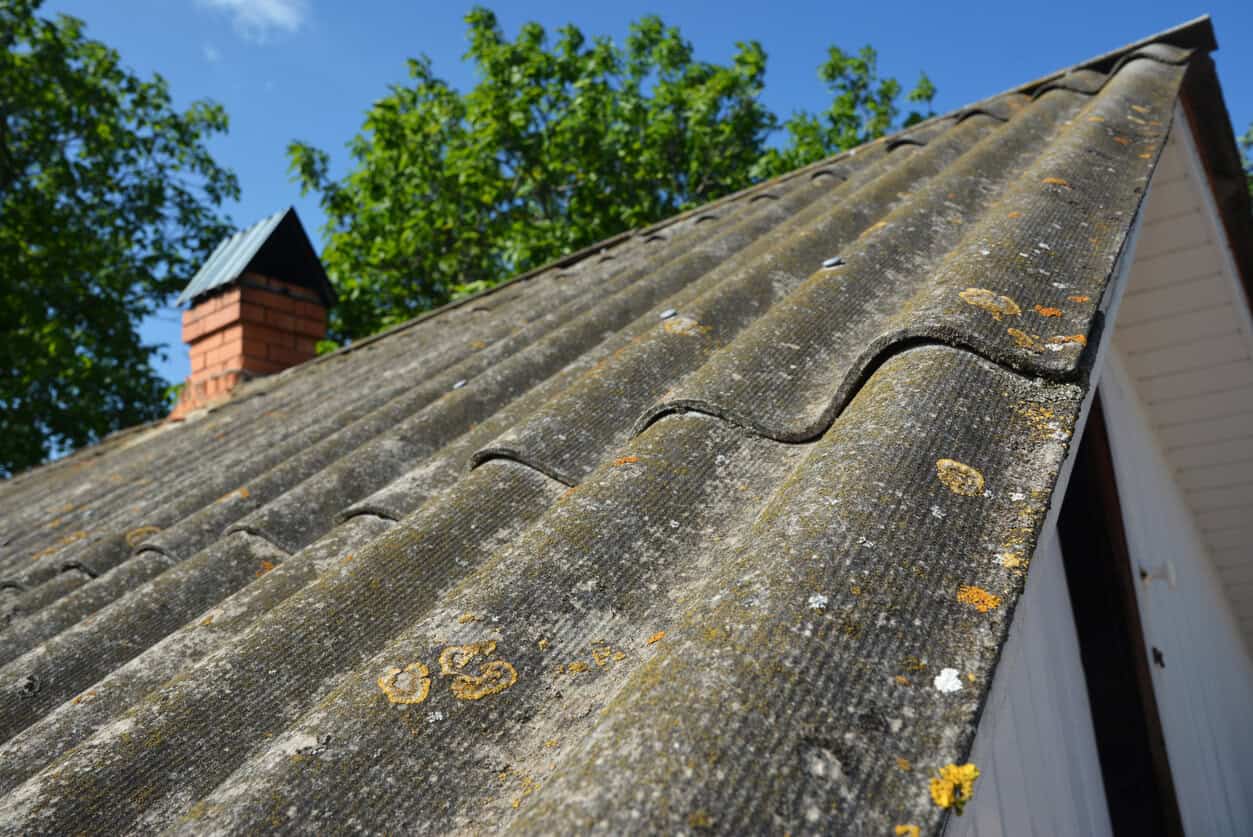An old asbestos pitched roof. A close-up of an old asbestos roof tiles covered with moss and lichen.