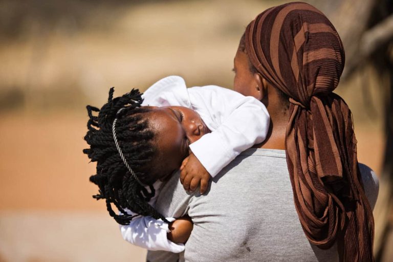 An African woman carrying her sleeping baby girl
