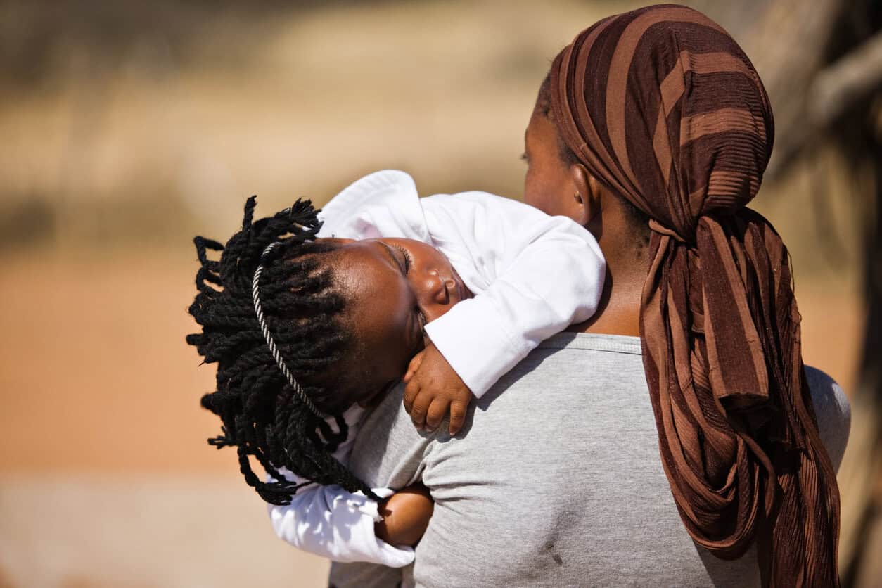 An African woman carrying her sleeping baby girl