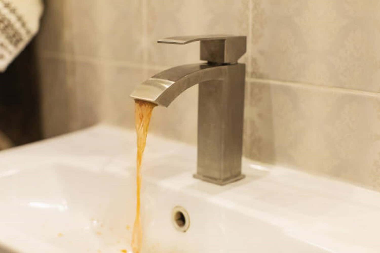 Dirty rusty water flows from faucet.